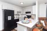 Located at 424 N 300 E St in Provo, Utah, this single-floor unit offers a practical and well-designed layout that makes efficient use of its space. The living area welcomes you with warm wood-look flooring, a textured ceiling, and a window with blinds and drape panels that allow for natural light control. A wall-mounted HVAC unit provides climate comfort, while the open layout connects seamlessly to the kitchen.

The kitchen is outfitted with white cabinetry, black appliances including a full-size refrigerator, electric range, and dishwasher, as well as a peninsula counter with bar seating — ideal for casual dining or meal prep. The clean white countertops and under-cabinet range hood complete the functional cooking space.

The bedroom features plush wall-to-wall carpet, a ceiling fan with light fixture, a window with blinds and drape panels for natural light, and a closet with sliding doors offering generous storage. Adjacent to the bedroom, the bathroom includes a white vanity with sink and ample counter space.

Throughout the unit, wood-look flooring in the main living areas and carpet in the bedroom create a comfortable contrast, while neutral wall tones provide a versatile backdrop. This well-appointed space combines functionality and comfort in a convenient Provo location.