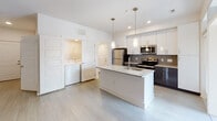Located at 411 Flemington Rd in Chapel Hill, NC, this well-appointed single-floor residence offers a thoughtfully designed layout with modern finishes throughout. The open-concept kitchen serves as the heart of the home, featuring two-tone cabinetry with crisp white upper cabinets and dark lower cabinets, granite countertops, a tile backsplash, stainless steel appliances, and a central island with pendant lighting — perfect for both cooking and casual dining. Light wood-style flooring flows seamlessly throughout the entire unit, creating a cohesive and contemporary feel. The living area is bright and airy, benefiting from recessed lighting and sliding glass doors that open to a private balcony with outdoor views. Bedrooms are comfortably sized and equipped with ceiling fans, while a generous walk-in closet with wire shelving provides ample storage. The bathrooms are finished with dark vanity cabinetry, granite countertops, and brushed nickel hardware; one features a soaking tub and shower combination, while the other offers a large mirror and vanity. A dedicated in-unit laundry closet with a full-size washer and dryer adds everyday convenience. Clean white walls and recessed lighting throughout contribute to a bright, modern ambiance.