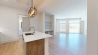 Located in Chamblee, GA, this well-appointed 3-bedroom, 2-bathroom residence offers a thoughtfully designed single-floor layout that maximizes both functionality and style. The open-concept kitchen and living area serves as the heart of the home, anchored by a striking oversized island with a white quartz countertop, an undermount sink, and warm wood cabinetry. Stainless steel appliances, a white subway tile backsplash, white upper cabinets, and a bold geometric pendant light fixture complete the modern aesthetic. The living room extends naturally from the kitchen, featuring light wood-style flooring, built-in shelving, and expansive windows with sliding glass door access to an outdoor balcony, flooding the space with natural light. The generously sized primary bedroom is carpeted for comfort, offering multiple windows, a sliding glass door to the balcony, and abundant natural light with outdoor views. Additional bedrooms also feature light wood-style flooring and bright, neutral walls. The two bathrooms are clean and modern — one featuring a white vanity with ample drawer storage and a framed mirror, and the other offering a full tiled tub-shower combination. A dedicated closet completes this well-organized, contemporary home.
