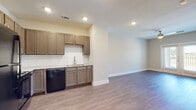 This single-floor unit offers a clean, contemporary design with an open-concept layout that seamlessly connects the kitchen and living areas. The kitchen is well-appointed with taupe shaker-style cabinetry, granite countertops, a white subway tile backsplash, and a full suite of black appliances including a refrigerator, gas range, microwave, and dishwasher. Recessed lighting throughout keeps the space bright and functional.

Consistent hardwood-style flooring flows through the entire unit, lending a cohesive and modern feel to every room. The spacious living area benefits from a ceiling fan and neutral wall tones that create a calm, inviting atmosphere. A dedicated entry foyer provides a clear transition from the front door into the main living space.

The bedroom is generously sized, featuring a large window with outdoor views of greenery that brings in ample natural light. A walk-in closet offers substantial storage. The bathroom is finished with a glass-enclosed walk-in shower clad in white tile, a granite-topped vanity with taupe cabinetry, and wood-look flooring that ties into the rest of the unit. Clean lines and neutral finishes throughout give the space a polished, move-in-ready appearance.