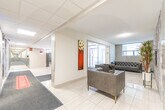 The lobby at 950 Warwick Crt in Burlington, Ontario is a well-appointed residential building entrance designed for both functionality and comfort. The space is finished with large-format light ceramic floor tiles accented by grey carpet runners that guide residents from the glass-panel front entrance toward the elevator bank. The entry area is highlighted by a set of stainless steel elevators framed by a striking textured stone mosaic feature wall, adding a modern design element to the space.

Natural light filters in through the glass front doors and a side window, keeping the lobby bright and inviting. Flush-mount ceiling lights provide consistent illumination throughout. A dedicated mailroom alcove houses a full wall of individual resident mailboxes, offering convenient mail access directly from the lobby.

A comfortable seating area is tucked to one side, furnished with tufted leather armchairs and a sofa set against warm wood-toned wall panels, creating a welcoming lounge space. Decorative touches, including potted plants and wall art, contribute to the polished, residential atmosphere. A mirrored console adds depth to the space. Additional utility areas and access doors are discreetly integrated into the layout, maintaining a clean and organized appearance throughout the lobby.