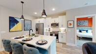 Located at 100 Fulton St SE in Atlanta's 30312 zip code, this single-floor residence offers a well-designed open-concept layout that seamlessly connects the kitchen, dining, and living areas. The kitchen is a standout feature, equipped with stainless steel appliances including a French door refrigerator, over-the-range microwave, and electric range, all framed by crisp white shaker cabinetry and a quartz waterfall island. Industrial-style pendant lights hang above the island, which provides additional seating. Light wood-look flooring runs throughout the main living areas, enhancing the bright, airy atmosphere. The living room benefits from multiple windows that allow generous natural light and offers views of surrounding greenery. Built-in shelving adds functional character to the transition between spaces. The bedrooms feature plush carpeting, ceiling fans, and windows dressed with blinds and curtain panels. The primary bedroom includes a bold accent wall and ample natural light. A secondary bedroom doubles effectively as a home office space. The bathroom is finished with wood-look flooring, a combination tub and shower with subway tile surround, and matte black fixtures. Throughout the residence, thoughtfully curated accent walls and contemporary artwork contribute to a vibrant, modern aesthetic.