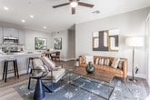 Located in Scottsdale, AZ, this well-appointed single-floor residence offers a thoughtfully designed open-concept layout that seamlessly connects the kitchen, dining, and living areas. The kitchen is fully equipped with stainless steel appliances, including a refrigerator, range, and microwave, complemented by soft gray shaker cabinetry, white quartz countertops, and a breakfast bar with seating. Wood-look flooring flows throughout the main living areas, adding warmth and continuity to the space. The living room features crown molding, a ceiling fan, and a sliding glass door that opens to a private patio, bringing in natural light and outdoor views. A dedicated dining nook provides an intimate space for everyday meals. The bedroom is a serene retreat finished with plush carpet, a ceiling fan, large windows dressed with navy blackout curtains, and direct access to a walk-in closet. The bathroom includes a full tub-shower combo and connects conveniently to the closet. Throughout the residence, neutral gray tones, recessed lighting, and clean architectural lines create a modern, cohesive aesthetic well-suited to the Scottsdale lifestyle.