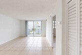 Located in Sunrise, FL, this well-appointed one-bedroom, one-bathroom unit offers a bright and efficiently designed single-floor layout. Light-toned ceramic tile flooring runs throughout the entire space, contributing to a clean, cohesive aesthetic. The combined living and dining area is generously proportioned, filled with natural light from a large sliding glass door that opens directly onto a private balcony with outdoor views of surrounding greenery. The kitchen features white cabinetry with modern hardware, a stainless steel sink with a pull-down faucet, white countertops, and a dishwasher, connected to the main living area via a pass-through window. The bedroom is a well-sized, private retreat with a dedicated window that invites natural light, and is served by a hallway that leads to the bathroom. The bathroom is a standout feature, finished with elegant marble-style tile on both the floors and walls, complemented by a soaking tub and shower combination. Multiple closets are distributed throughout the unit, providing ample storage. The entrance opens into a welcoming hallway that transitions smoothly into the main living space, creating a logical and functional flow throughout.