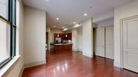 This one-bedroom, one-bathroom unit in New Orleans, Louisiana offers a thoughtfully designed single-floor layout with a cohesive aesthetic throughout. Rich hardwood flooring extends across the living, kitchen, and bedroom areas, creating a warm and consistent visual flow. Neutral beige walls and recessed lighting throughout provide a clean, versatile backdrop.

The open-concept living area is spacious and well-lit, anchored by large black-framed windows that allow natural light to filter in from an adjacent courtyard. The kitchen is a functional standout, featuring rich dark wood cabinetry, granite countertops, stainless steel appliances including a refrigerator, range, and microwave, and a kitchen island with pendant lighting overhead. An in-unit washer and dryer are conveniently tucked just off the kitchen.

The bedroom is generously sized with a ceiling fan, a large courtyard-facing window, and direct access to a closet. The bathroom is finished with granite countertops, a white vanity, and tile flooring. The unit offers a well-balanced combination of practical features and polished finishes suited for urban living in the heart of New Orleans.