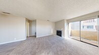 Located at 5150 E Sahara Ave in Las Vegas, NV, this one-bedroom, one-bathroom unit offers a practical and comfortable layout across a single floor. The living room serves as the heart of the space, featuring plush carpet flooring, a classic fireplace with a white mantel, and a sliding glass door that opens onto a private balcony, filling the room with natural light. A ceiling fan in the dining area aids airflow between the living and kitchen spaces. The kitchen is efficiently designed in a U-shape with white cabinetry, granite-style countertops, a breakfast bar, and white appliances including a range and refrigerator, all set on light tile flooring. A window above the sink adds natural light to the kitchen. The bedroom is a comfortable size, highlighted by a charming arched window that brings in ample daylight, with soft carpet underfoot and two closets providing generous storage. The bathroom is clean and functional, featuring a tub/shower combo, a vanity with granite-style countertops, and a stacked washer/dryer unit, conveniently combining laundry within the bathroom. Neutral tones, textured ceilings, and tile flooring in wet areas complete the practical, well-organized layout of this Las Vegas residence.