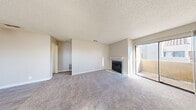 Located at 5150 E Sahara Ave in Las Vegas, NV, this one-bedroom, one-bathroom unit offers a practical and comfortable layout across a single floor. The living room serves as the heart of the space, featuring plush carpet flooring, a classic fireplace with a white mantel, and a sliding glass door that opens onto a private balcony, filling the room with natural light. A ceiling fan in the dining area aids airflow between the living and kitchen spaces. The kitchen is efficiently designed in a U-shape with white cabinetry, granite-style countertops, a breakfast bar, and white appliances including a range and refrigerator, all set on light tile flooring. A window above the sink adds natural light to the kitchen. The bedroom is a comfortable size, highlighted by a charming arched window that brings in ample daylight, with soft carpet underfoot and two closets providing generous storage. The bathroom is clean and functional, featuring a tub/shower combo, a vanity with granite-style countertops, and a stacked washer/dryer unit, conveniently combining laundry within the bathroom. Neutral tones, textured ceilings, and tile flooring in wet areas complete the practical, well-organized layout of this Las Vegas residence.