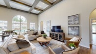 Located at 200 Buzz St in Branson, Missouri, this elegantly designed single-floor space offers a seamless blend of architectural charm and functional comfort. The grand entryway sets the tone immediately, featuring soaring ceilings, rich hardwood-style flooring, and a sweeping arched passage that draws the eye toward the main living area.

The living room is a standout, showcasing a dramatic coffered ceiling with dark wood beam detailing and recessed lighting that adds depth and warmth. Generous seating arrangements, a media console, and curated artwork create an inviting, well-organized gathering space. Arched doorways and alcoves throughout reinforce a cohesive architectural theme.

The adjacent dining area is bathed in natural light, thanks to a striking floor-to-ceiling arched window flanked by additional windows, all offering direct views of an outdoor pool and surrounding landscaping. Multiple dining tables provide ample seating for group gatherings.

The kitchen is accessed through an arched opening and features warm wood cabinetry, light stone countertops, tile flooring, and a breakfast bar with barstool seating—practical and efficiently laid out for serving a crowd.

Additional seating nooks with upholstered chairs offer quieter spaces for relaxation. Throughout, the neutral color palette, natural light, and consistent architectural details create a cohesive and welcoming ambiance.