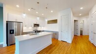 Located at 5126 Peachtree Blvd in Chamblee, Georgia, this single-floor residence offers a thoughtfully designed open layout with contemporary finishes throughout. Warm-toned hardwood flooring flows seamlessly across every room, anchoring the bright, clean aesthetic defined by crisp white walls and modern trim details.

The kitchen serves as the centerpiece of the space, featuring a large island with a white quartz countertop and undermount sink, two-tone cabinetry pairing white upper cabinets with gray lower cabinets, stainless steel appliances, and stylish globe pendant lights. Recessed lighting adds additional brightness throughout.

The living area is highlighted by a wall of large floor-to-ceiling windows that invite abundant natural light and provide views of the surrounding outdoor greenery. An elegant board-and-batten accent wall and a ceiling fan contribute to the room's refined, contemporary character.

The hallway features a built-in niche, adding a subtle architectural detail. Bedrooms are well-proportioned and include ceiling fans. The walk-in closet is outfitted with a multi-tiered shelving and hanging rod system, offering generous storage capacity.

The bathrooms are finished with gray vanity cabinetry, white quartz countertops, framed mirrors, brushed gold fixtures, and clean tile surrounds. The overall ambiance of the space is modern, light-filled, and move-in ready.
