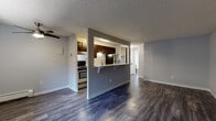 Located at 7781 W 52nd Ave in Arvada, Colorado, this single-floor residence offers a well-organized layout with a clean, modern aesthetic. The open living area is finished with rich, dark hardwood-style flooring and features a ceiling fan, a wall-mounted air conditioning unit, and a baseboard heating system, ensuring year-round comfort. Natural light filters in through a front-facing window, brightening the space considerably.

The kitchen is accessed via a half-wall pass-through with a breakfast bar, creating an open and connected feel between the kitchen and living areas. Inside, dark-toned cabinetry pairs with light speckled countertops and a stainless steel sink. The kitchen is equipped with stainless steel appliances, including a gas range and refrigerator, along with a dishwasher for added convenience.

The bedroom is carpeted for warmth and comfort, featuring baseboard heating and a window with a pleasant view of surrounding greenery, lending a peaceful, natural atmosphere to the room.

The bathroom is finished with hardwood-style flooring matching the main living area. It includes a tub-shower combination with tiled surround, a toilet, and a dark wood vanity with a light countertop. A window provides natural light, keeping the space bright and airy. The textured ceilings throughout add a consistent architectural detail across all rooms.