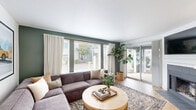 Located in Vancouver, WA, this single-floor, 2-bedroom, 2-bathroom home offers a thoughtfully designed layout with modern finishes throughout. The living room is a welcoming centerpiece, featuring light hardwood flooring, a tiled fireplace, and large sliding glass doors that invite natural light and provide access to an outdoor area. A second set of windows brings additional brightness, enhancing the open, airy feel of the space.

The kitchen is fitted with crisp white shaker-style cabinetry, white countertops, stainless steel appliances, and a pass-through window that connects seamlessly to the dining area — a charming detail that promotes an open flow between spaces. The dining area accommodates comfortable seating and is accented by a modern pendant light fixture and a bold sage-green accent wall.

The primary bedroom is a well-sized retreat with large windows, light hardwood floors, a bold blue accent wall, and direct access to one of the two bathrooms. The second bedroom features a gray accent wall and a closet. Both bathrooms are clean and functional — one with a soaking tub and white vanity cabinetry, the other with a walk-in shower. A dedicated in-unit laundry area with a full-size washer and dryer adds everyday convenience.
