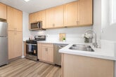 This 680-square-foot, single-floor apartment at 6233 S La Brea Ave in Inglewood, CA offers a well-planned layout with 2 bedrooms, 1 bathroom, a living room, kitchen, and hallway. Consistent wood-style flooring and neutral gray walls create a cohesive, modern aesthetic throughout the unit. The bright living room features a large sliding window that invites natural light and street views. The hallway entry is accented by a stylish chandelier, connecting the space with a welcoming transition. The kitchen is efficiently designed with light wood cabinetry, white quartz countertops, and a full suite of stainless steel appliances including a refrigerator, gas range, microwave, and dishwasher. Both bedrooms are well-lit with large windows offering outdoor views; the primary bedroom measures 120 square feet and includes a ceiling fan and a built-in closet with sliding doors and upper cabinet storage. The second bedroom also benefits from generous natural light. The bathroom is clean and functional, featuring a full tub-shower combo and a vanity with light wood cabinetry and a white countertop. The unit's clean finishes and practical layout make it a comfortable and functional living space.