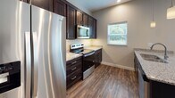 Located at 108 Colonial Dr in Findlay, Ohio, this two-story home presents a thoughtfully designed layout with contemporary finishes throughout. The main level features an open living area with durable wood-look flooring, recessed lighting, and a ceiling fan, creating a bright and functional space. A conveniently located half bathroom is tucked near the staircase on this floor.

The kitchen is well-equipped with dark espresso cabinetry, granite countertops, and a full suite of stainless steel appliances, including a refrigerator with ice dispenser, electric range, and built-in microwave. A window above the counter brings in natural light, adding to the kitchen's inviting atmosphere.

Upstairs, multiple carpeted bedrooms each feature ceiling fans and windows that allow natural light to filter in. Two full bathrooms serve the upper level—one with a walk-in glass-door shower and another with a tub-shower combination—both finished with dark cabinetry and granite countertops atop tile flooring. A dedicated laundry area rounds out the home, complete with a full-size washer and dryer, wire shelving, and utility access, offering added everyday convenience.