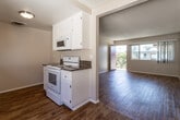 Located at 1031 W B St in Ontario, California, this single-floor unit offers a well-organized layout with a variety of functional living spaces. Rich wood-look flooring extends throughout the main living and dining areas, creating a warm and cohesive aesthetic. Textured ceilings are present throughout, adding a classic residential character.

The open living area is generously proportioned, filled with natural light from sliding windows dressed with vertical blinds. A distinctive accent wall in warm gold ties the living and dining areas together, while a ceiling fan with light fixture serves the dining space. A sliding glass door leads to an outdoor area, bringing in additional light and views of surrounding greenery.

The galley-style kitchen is efficiently designed with white cabinetry, dark granite countertops, a double-basin sink, white appliances including a range, microwave, and dishwasher, and continued wood-look flooring underfoot.

The bedrooms feature plush carpeting and ceiling fans, providing comfort and quiet. One bedroom includes access to a walk-in closet area, adding practical storage. The bathroom is well-appointed with white cabinetry, dark granite countertops, a combination shower/tub with glass sliding doors, and a window that brings in natural light.
