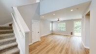 This two-story home in Huntsville, AL offers a clean, modern aesthetic with high-quality finishes throughout. The main floor features an open living area with warm luxury vinyl plank flooring, soaring ceilings, recessed lighting, and a ceiling fan. Large windows with blinds invite abundant natural light and offer views of the surrounding greenery. A staircase with carpeted treads and a white balustrade connects both levels with architectural charm.

The kitchen is well-equipped with white shaker cabinetry, granite countertops, stainless steel appliances including a range, microwave, refrigerator, and dishwasher, complemented by a deep double sink with a matte black faucet and luxury vinyl plank flooring.

Upstairs, the primary bedroom is a comfortable retreat featuring plush carpeting, a ceiling fan, and a dedicated ensuite bathroom. The ensuite offers a dual-sink granite vanity with white cabinetry, matte black fixtures, and a walk-in shower. Additional bedrooms are generously sized with carpeted floors and ceiling fans. All three bathrooms maintain a consistent design with granite countertops and wood-tone flooring. Double Craftsman-style closet doors provide ample storage. The home's neutral gray palette and matte black hardware accents deliver a cohesive, contemporary feel throughout.