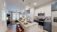 Located at 3229 W Montague Ave in North Charleston, SC, this 2-bedroom, 1-bathroom residence offers a thoughtfully designed single-floor layout with contemporary finishes throughout. The open-concept kitchen serves as a centerpiece of the home, featuring granite countertops, a large island with bar seating, pendant lighting, white upper cabinetry, contrasting navy lower cabinets, and a full suite of stainless steel appliances. The kitchen flows seamlessly into the living room, which is bathed in natural light from large windows and accented by wood-look flooring and a ceiling fan. The primary bedroom offers a comfortable, carpeted retreat with ample space, while the second bedroom also features carpet flooring, a ceiling fan, and a bright window with outdoor views. The full bathroom includes a double-sink granite vanity with navy cabinetry, a glass-enclosed walk-in shower, and wood-look flooring. Two closets provide generous storage, including a walk-in closet outfitted with multi-tier wire shelving. Clean neutral walls, consistent modern finishes, and a practical layout make this residence a functional and attractive living space.