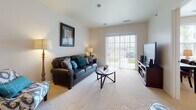Located at 1740 Eden Park Dr in Hamilton, Ohio, this single-floor residence offers a thoughtfully designed layout that balances comfort and functionality. The kitchen is equipped with warm cherry-toned cabinetry, granite-style countertops, and stainless steel appliances including a refrigerator, range, microwave, and dishwasher, all set atop durable tile flooring. Adjacent to the kitchen, the dining area features plush carpeting, a pendant light fixture, and a breakfast bar that connects seamlessly to the main living spaces. The living room is bright and welcoming, with large sliding glass doors that allow generous natural light and provide direct access to an outdoor area. Soft carpeting and neutral wall tones create a relaxed, inviting atmosphere throughout. Two bedrooms offer comfortable retreats, each with plush carpeting, natural light from windows, and closet storage. The primary bedroom includes a walk-in closet and well-proportioned layout. The bathroom is finished with stone-look tile flooring, a wood-toned vanity, a walk-in shower with sliding glass doors, and safety grab bars, making it both stylish and accessible. The overall design emphasizes ease of living within a clean, neutral aesthetic.