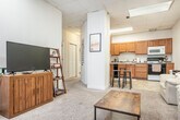 Located at 635 Langdon St in Madison, WI, this three-bedroom, one-bathroom unit is spread across a single floor and offers a functional, well-organized layout. The open-concept living and kitchen area forms the heart of the home, where a structural column subtly defines the two spaces without closing them off. The kitchen is equipped with warm honey-toned wood cabinetry, a full suite of appliances including a range, microwave, and dishwasher, and a tile floor that extends throughout the space. A breakfast bar with stools provides a casual dining option. The living area features plush carpeting and benefits from natural light streaming through a striking arched window — a standout architectural detail that adds character to the space. The front entry also features this same decorative arched window, creating a welcoming first impression. Each of the three bedrooms is carpeted and offers closet storage, with the generously sized primary bedroom showcasing wainscoting details and its own arched window. The shared full bathroom includes a single-sink oak vanity, tiled flooring, and a shower-tub combination. Two hallways connect the rooms efficiently, and a dedicated closet provides additional storage. The drop-panel ceiling with integrated lighting is consistent throughout the unit.