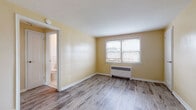 Located at 1093 Sheridan Ave in Elizabeth, NJ, this single-floor unit offers a clean, functional layout designed for comfortable everyday living. The living and bedroom areas are finished with light gray wood-style flooring that lends a modern, cohesive look throughout. Warm yellow-toned walls and white trim create a bright, welcoming ambiance, while multiple windows fitted with blinds allow for natural light and neighborhood views.

Each room is equipped with a baseboard radiator, providing consistent heating throughout the unit. The kitchen stands out with its dark espresso-toned shaker cabinetry, granite countertops, a white subway tile backsplash, stainless steel appliances including a gas range and refrigerator, and a single-basin undermount sink. Light tile flooring in the kitchen complements the cabinetry for a polished finish.

The bathroom features full wall tiling in a neutral cream palette, a soaking bathtub with an overhead shower, a white vanity with cabinet storage, and tile flooring — offering a clean and functional space. The overall floor plan, visible in the dollhouse view, presents a compact yet efficient arrangement with well-defined living, sleeping, kitchen, and bathroom areas, making this unit practical and move-in ready.