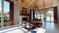 Located at 1658 S Hiawassee Rd in Orlando, this single-story space showcases an impressive architectural design centered around dramatic vaulted ceilings with exposed wooden beam framework and natural wood paneling overhead. The expansive main living area commands immediate attention with its towering ceiling height, anchored by a striking floor-to-ceiling stone fireplace that serves as the room's focal point. Large floor-to-ceiling windows and glass doors flood the interior with abundant natural light while offering direct views of and access to the outdoor area beyond, creating a seamless indoor-outdoor flow.

The living area features polished stone tile flooring throughout, contributing to the space's open, airy atmosphere. Ceiling fans are integrated into the beam structure, enhancing both function and aesthetic. The reception and administrative area includes warm wood cabinetry with a built-in workstation, complemented by light blue accent walls and continued vaulted wood ceilings. A corridor with recessed lighting connects functional areas, maintaining the consistent use of tile flooring and natural materials. Throughout the space, the combination of stone, wood, and expansive glazing creates a cohesive, welcoming ambiance with a distinctive Southwest-inspired architectural character.