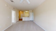 Located at 11390 US-19 N in Port Richey, Florida, this two-bedroom, one-bathroom residence offers a practical and comfortable single-floor layout. The open-concept design connects the kitchen and living/dining area seamlessly, creating a bright and functional shared space. The kitchen features white cabinetry, a peninsula with a double sink and extended countertop, a dishwasher, and a range, with wood-look flooring that transitions into plush neutral carpet in the living areas. Crown molding accents the living room, which is equipped with a ceiling fan and a sliding glass door that invites natural light and provides outdoor access. Both bedrooms are carpeted and feature ceiling fans, with windows fitted with horizontal blinds for light control. The primary bedroom offers a generous footprint with good natural light. The bathroom is well-appointed with white cabinetry, a vanity with a broad mirror, tile flooring, and a tub/shower combination. The space also includes an impressive seven closets, providing exceptional storage throughout. Warm, cream-toned walls and consistent neutral finishes give the entire residence a clean, cohesive aesthetic.