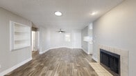This single-floor residence offers a clean, modern aesthetic with a neutral color palette and durable wood-look flooring that flows throughout the main living areas. The spacious living room is a standout, featuring a ceiling fan, a tiled fireplace, built-in wall shelving, and a sliding glass door that opens to an outdoor patio, filling the space with natural light. An adjacent area with additional built-in shelving provides flexible use as a dining or sitting space.

The kitchen is thoughtfully designed with crisp white cabinetry, light countertops, and a full suite of stainless steel appliances, including a refrigerator, range, microwave, and dishwasher. A window above the sink adds natural light, and a breakfast bar offers casual seating and connectivity to the living area.

The bedrooms feature plush carpeting, ample natural light from large windows, and generous closet space. Two full bathrooms serve the residence — one with a tub-shower combination and white vanity cabinetry, and another with a walk-in shower and a large mirror above the vanity. A dedicated in-unit laundry room with overhead cabinetry and a full-size washer and dryer adds exceptional everyday convenience. The textured ceilings and clean white trim complete the polished, move-in-ready presentation throughout.