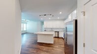 Located at 2600 S Blue Angel Pkwy in Pensacola, Florida, this single-floor residence offers a clean, modern aesthetic with thoughtfully designed living spaces. The open-concept kitchen serves as the heart of the home, showcasing crisp white shaker cabinetry, light granite countertops, a white subway tile backsplash, and a full suite of stainless steel appliances including a side-by-side refrigerator with ice maker, electric range, built-in microwave, and dishwasher. A central island with a matching granite surface provides additional prep space and casual seating. Rich wood-look flooring runs throughout the main living areas, complementing the bright, neutral color palette. The living area is open and airy, with a ceiling fan and recessed lighting adding comfort and functionality. Bedrooms are carpeted for warmth and comfort, with corner windows that invite natural light, ceiling fans, and walk-in closets offering generous storage. The bathroom features a dual-sink vanity topped with granite, white cabinetry, and a tub-shower combination. Throughout the space, the consistent use of white finishes, granite surfaces, and modern fixtures creates a cohesive and polished interior that is both functional and inviting.