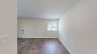 Located along Eliots Oak Road in Columbia, Maryland, this single-story unit offers a well-organized layout with a clean, updated interior throughout. The main living areas feature rich, wood-look plank flooring laid in a staggered pattern, contributing a warm and cohesive aesthetic. Neutral white walls and white trim provide a bright, versatile backdrop across the space.

The kitchen is a functional highlight, showcasing rich cherry-toned cabinetry, granite countertops with a complementary tile backsplash, and stainless steel appliances including a refrigerator and dishwasher. Recessed lighting and a pendant fixture illuminate the space, while a central island adds additional prep and storage capability. A sliding glass door opens directly to the outdoors, where surrounding greenery is visible, bringing natural light into the adjacent dining area.

Bedrooms are finished with neutral carpet, offering a comfortable, quiet feel, and are served by two bathrooms. One bathroom features a tiled tub-and-shower combination with a decorative mosaic border accent, granite vanity, and tile flooring. The second bathroom includes a walk-in glass shower enclosure. An in-unit laundry area adds further everyday convenience to this thoughtfully updated space.