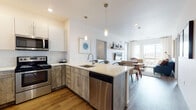 This well-appointed single-floor residence at 1315 Nelson St in Lakewood, Colorado offers a thoughtfully designed open-concept layout with contemporary finishes throughout. The kitchen serves as a functional centerpiece, featuring stainless steel appliances including a range, microwave, dishwasher, and refrigerator. Two-tone cabinetry pairs weathered wood-look lower cabinets with crisp white uppers, complemented by light quartz countertops and a peninsula with an undermount sink. Warm hardwood-style flooring flows through the main living areas.

The living area benefits from floor-to-ceiling windows that frame sweeping panoramic views of the surrounding Lakewood landscape, filling the space with abundant natural light. Multiple bedrooms are carpeted for comfort, each featuring large windows with the same impressive outlooks. One bedroom is distinguished by a bold geometric accent wall, adding visual interest. The primary bathroom includes an extended vanity with wood-tone cabinetry, quartz counters, a large mirror, and direct access to a walk-in closet. A second full bathroom offers a tub-shower combination with tile surround and hardwood-style flooring. The overall aesthetic is clean, modern, and bright throughout.