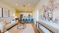 Located at 1830 Autumn Dr in Hoffman Estates, IL, this single-floor, three-bedroom, two-bathroom home offers a well-designed open-concept layout with modern finishes throughout. Light wood-style flooring flows through the main living areas, complementing the neutral color palette that gives the space a clean, contemporary feel.

The living room is bright and inviting, with large windows that allow natural light to fill the space. It connects seamlessly to the dining area and kitchen, creating an ideal environment for everyday living and entertaining. The kitchen is a standout feature, centered around a large island with a white countertop and seating for multiple bar stools. White cabinetry extends to the ceiling, pendant lighting accents the island, and stainless steel appliances complete the functional setup. A stacked washer and dryer unit is conveniently integrated near the dining area.

The primary bedroom is a comfortable retreat with neutral carpet, generous proportions, and natural light. Additional bedrooms share similar finishes with carpeted floors and well-sized windows with outdoor views. The two bathrooms are finished with wood-look tile flooring and gray cabinetry — one featuring a walk-in glass shower, the other a full tub-shower combination.