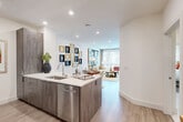 Located in Charlotte's vibrant South End neighborhood, this 1-bedroom, 1-bathroom residence offers a thoughtfully designed open-concept layout that maximizes every square foot. Light wood-style flooring flows throughout, complementing the clean, modern aesthetic found in every room.

The kitchen is a functional centerpiece, featuring sleek wood-grain cabinetry, white quartz countertops, a stainless steel appliance suite including a French door refrigerator, microwave, and range, and a peninsula with an undermount sink that opens seamlessly to the dining and living areas. A built-in desk nook provides a convenient workspace just off the kitchen.

The living room is bright and inviting, with large floor-to-ceiling windows and access to a private balcony that fills the space with natural light and outdoor views. Recessed lighting and crisp white walls enhance the open, airy atmosphere.

The bedroom offers a comfortable retreat with a ceiling fan, generous window with exterior views, and two closets for ample storage. A hallway with elegant marble-look tile flooring leads to the full bathroom, with additional closet access along the way.

This residence combines modern finishes with a practical, well-organized floor plan, making it an ideal home in one of Charlotte's most sought-after locations.