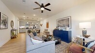 This two-story home in Denton, TX offers a thoughtfully designed layout spread across two floors. The main level features an open-concept living, dining, and kitchen area bathed in natural light, with light wood-look flooring flowing throughout. The living room is anchored by a ceiling fan and connects seamlessly to the dining space and kitchen. The kitchen is well-equipped with gray shaker-style cabinetry, dark granite-style countertops, stainless steel appliances including a refrigerator, microwave, and dishwasher, and pendant lighting above the counter. A hallway and one of three bathrooms round out the main floor.

Upstairs, two carpeted bedrooms provide comfortable retreats, each with natural light from large windows with blinds. The primary bedroom includes an en-suite bathroom with gray cabinetry and dark countertops, as well as a dedicated walk-in closet with built-in shelving and hanging rods. The additional bathroom features a tub-shower combo with clean white subway tile surround, gray cabinetry, and wood-look flooring. A staircase connects the two levels, and a hallway closet provides additional storage. The home's neutral palette and consistent finishes create a cohesive, modern aesthetic throughout.