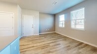 Located at 4700 Wagon Rd in Santa Fe, NM, this well-designed single-floor unit offers 1 bedroom and 2 bathrooms within a efficiently utilized floor plan. The open-concept kitchen serves as the centerpiece of the living space, showcasing white shaker cabinetry extending to the ceiling, a large quartz waterfall island with an integrated sink, stainless steel appliances including a full-size refrigerator and range, a subway tile backsplash, and stylish black pendant lighting overhead. Light wood-look flooring runs throughout the main living areas, complementing the neutral gray walls and creating a bright, contemporary feel. The living area features natural light through multiple windows with blinds and direct access to an outdoor balcony. The bedroom is carpeted and comfortably sized, with ample natural light from multiple windows and closet access. Both bathrooms are designed with accessibility in mind, featuring grab bars, a roll-in shower with a fold-down bench and handheld showerhead in one bathroom, and light wood flooring with clean white finishes throughout. The overall design is modern, clean, and functional, with thoughtful accessibility features integrated seamlessly into the aesthetic.