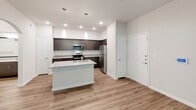 This single-story residence on Edgeworth Bend in Austin, TX offers a clean, contemporary design with a neutral color palette throughout. The open-concept layout connects the living area to the kitchen seamlessly, with warm wood-look flooring running across both spaces. An arched doorway adds a subtle architectural detail, while recessed lighting and pendant lights above the kitchen island provide layered illumination.

The kitchen is well-appointed with dark espresso cabinetry featuring sleek hardware, light granite countertops, a subway tile backsplash, and a full suite of stainless steel appliances including a refrigerator, range, and microwave. A central island with an integrated sink and granite surface offers additional workspace and casual dining potential.

Bedrooms feature plush carpeting, ceiling fans, and windows with blinds that allow natural light while maintaining privacy. The bathroom includes a combination tub and shower, a granite-topped vanity with dark cabinetry, wood-look flooring, and a clean, functional layout. The overall ambiance is modern and move-in ready, with consistent finishes tying each room together cohesively.