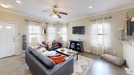 This two-story home offers a thoughtfully designed layout across two levels, combining comfort and functionality throughout. The main floor features a bright and welcoming living room adorned with crown molding, recessed lighting, and a ceiling fan, with multiple windows dressed in sheer curtains and blinds that allow natural light to fill the space. Adjacent to the living area, the combined kitchen and dining room provide an ideal setup for everyday living and entertaining. The kitchen is equipped with dark cabinetry, a subway tile backsplash, a full suite of black appliances, and a window above the sink. A chandelier-lit dining area with direct access to the staircase completes the ground floor.

Upstairs, the generously sized primary bedroom features wall-to-wall carpet, multiple windows with sheer curtains, and a walk-in closet outfitted with wire shelving and a built-in shelving unit. Two additional bedrooms offer comfortable accommodations with ceiling fans and carpeted floors. All three bathrooms are well-appointed with wood-style flooring and vanities. A dedicated laundry room houses a full-size washer and dryer, adding everyday convenience. The home's warm, neutral palette and practical layout make it a functional and inviting residence.