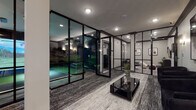 Located at 8 Tice Rd in Franklin Lakes, NJ, this single-floor entertainment facility is thoughtfully designed to deliver a premium recreational experience. The space is defined by a striking contemporary aesthetic, anchored by floor-to-ceiling black-framed glass partition walls that divide the various zones while maintaining a sense of openness and visual connectivity throughout.

The centerpiece of the facility is a state-of-the-art indoor golf simulator room, complete with a full driving bay, a large projection screen displaying realistic course imagery, a putting green with synthetic turf, and golf-themed wall murals. The simulator bay is equipped with professional lighting and a dedicated mini-split HVAC unit for climate control.

Adjacent to the golf simulator, a sophisticated lounge area features textured carpet flooring, a sleek black coffee table, and comfortable seating arranged for socializing. The lounge connects seamlessly through the glass partitions to a smaller secondary seating area furnished with a wall-mounted display and a credenza, accented by a decorative indoor plant.

A dedicated screening room rounds out the facility, outfitted with a row of premium black leather power recliner seats featuring illuminated cup holders and blue LED accent lighting beneath. A large wall-mounted television anchors the room, while a wall sconce and mini-split unit complete the cinema-like atmosphere. Throughout the space, recessed lighting and carefully placed wall sconces create a polished, upscale ambiance.