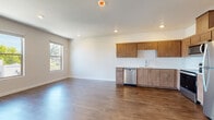 Located in Portland, Oregon, this single-floor unit offers a clean, contemporary design with a cohesive palette of neutral tones and warm wood finishes throughout. The open-concept living and kitchen area is anchored by rich hardwood-style flooring that extends seamlessly across the space, creating a unified and inviting atmosphere. Large windows allow generous natural light to fill the interior, offering views of the surrounding greenery and neighborhood rooftops.

The kitchen is well-appointed with warm wood-tone cabinetry extending to the upper reaches of the walls, white countertops, and a full suite of stainless steel appliances including a refrigerator, electric range, over-the-range microwave, and dishwasher. A functional layout maximizes counter and storage space.

The living area is open and versatile, with recessed lighting and clean white walls that provide a bright, adaptable canvas. A private bedroom features dual windows with neighborhood views, recessed lighting, and the same hardwood-style flooring found throughout.

The unit includes two bathrooms: one with a walk-in shower featuring white tile surround and a wood-tone vanity with white countertop, and a second with a full soaking tub and shower combination. A hallway with panel-style doors provides access to the various rooms, contributing to the unit's efficient and well-organized flow.