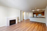 Located in Seattle's vibrant Lower Queen Anne neighborhood, this well-appointed one-bedroom, one-bathroom residence offers a thoughtfully designed layout with warm hardwood flooring throughout. The open-concept living and kitchen area serves as the heart of the home, featuring a classic fireplace with a clean white mantel, track lighting, and large windows that invite abundant natural light. Sliding glass doors lead to a private balcony, where lush tree canopies frame a stunning direct view of the iconic Space Needle — a truly standout feature of this space.

The kitchen is equipped with stainless steel appliances, including a full-size refrigerator, gas range, built-in microwave, and dishwasher. Rich wood cabinetry pairs with dark stone countertops and a peninsula with a double sink, creating a functional and stylish workspace. Track lighting overhead ensures the kitchen is always well-lit.

The bedroom is a comfortable, well-proportioned retreat with a large window overlooking greenery and baseboard heating. Three closets provide generous storage throughout the unit. A full bathroom and additional unclassified room round out the floor plan. Clean neutral tones and consistent hardwood flooring create a cohesive, modern aesthetic throughout the entire residence.