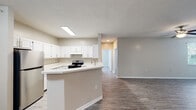 Located at 1856 Bordeaux Blvd in Burlington, Kentucky, this single-floor residence offers a clean, modern aesthetic defined by neutral tones, hardwood-style flooring, and an abundance of natural light throughout. The open-concept kitchen is a central highlight, featuring crisp white cabinetry, light countertops, a peninsula with a built-in sink, and stainless steel appliances including a refrigerator and electric range. The kitchen flows seamlessly into the living and dining areas, creating a connected and functional layout well-suited for everyday living. The spacious living area is finished with durable hardwood-style flooring, a ceiling fan, and windows fitted with blinds that allow for generous natural light. Multiple bedrooms offer comfortable, well-proportioned spaces, each with hardwood-style flooring and windows that bring in outdoor views. Two full bathrooms are finished with white vanities, tub-shower combinations, brushed nickel fixtures, and hardwood-style flooring, providing a consistent and polished look. Throughout the home, textured ceilings, clean white trim, and a cohesive warm-neutral color palette contribute to a bright and inviting atmosphere. The single-level layout ensures easy accessibility and a practical flow between all areas of the home.
