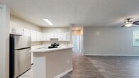 Located at 1856 Bordeaux Blvd in Burlington, Kentucky, this single-floor residence offers a clean, modern aesthetic defined by neutral tones, hardwood-style flooring, and an abundance of natural light throughout. The open-concept kitchen is a central highlight, featuring crisp white cabinetry, light countertops, a peninsula with a built-in sink, and stainless steel appliances including a refrigerator and electric range. The kitchen flows seamlessly into the living and dining areas, creating a connected and functional layout well-suited for everyday living. The spacious living area is finished with durable hardwood-style flooring, a ceiling fan, and windows fitted with blinds that allow for generous natural light. Multiple bedrooms offer comfortable, well-proportioned spaces, each with hardwood-style flooring and windows that bring in outdoor views. Two full bathrooms are finished with white vanities, tub-shower combinations, brushed nickel fixtures, and hardwood-style flooring, providing a consistent and polished look. Throughout the home, textured ceilings, clean white trim, and a cohesive warm-neutral color palette contribute to a bright and inviting atmosphere. The single-level layout ensures easy accessibility and a practical flow between all areas of the home.
