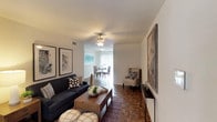 This thoughtfully designed 2-bedroom, 1-bathroom model unit spans a generous single-story floor plan, offering a comfortable and functional living environment. The open living and dining area serves as the heart of the home, featuring classic parquet wood flooring, a ceiling fan with light fixture, and a seamless flow between spaces. Large vertical-blind-covered sliding doors in the dining area allow abundant natural light to fill the room, creating a bright and welcoming atmosphere.

The kitchen is positioned adjacent to the dining area and features a pass-through counter with granite-style surfaces, rich wood cabinetry, white appliances, and a window for added ventilation and light.

Both bedrooms are well-proportioned, each equipped with ceiling fans, plush carpeting, and multiple windows that invite natural light. The primary bedroom includes a closet and direct access to the hallway, while the secondary bedroom also offers closet space and room for a dedicated sitting or study area.

The bathroom is clean and functional, featuring a granite-topped vanity with a large mirror, modern brushed-nickel fixtures, and a full tub-shower combination with tile surround.

Throughout the unit, a neutral color palette and consistent design elements create a cohesive, move-in-ready aesthetic suited for comfortable everyday living.