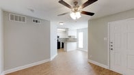 This well-designed single-floor, 1-bedroom, 1-bathroom unit offers a practical and comfortable living experience with a thoughtful layout. The open-concept living area flows seamlessly into the kitchen, creating a connected and functional space. Light wood laminate flooring runs throughout, contributing to a warm and inviting atmosphere. A ceiling fan with a built-in light fixture anchors the living area, providing both comfort and ambient lighting.

The kitchen features white cabinetry, a peninsula-style counter that separates it from the living space, and black appliances, including a range. A window above the sink allows natural light to brighten the kitchen area. The white walls and clean baseboards throughout give the unit a fresh, neutral aesthetic that is easy to personalize.

A hallway connects the living area to the private bedroom and bathroom, with a door offering separation between the spaces. The textured ceilings are consistent throughout, adding a subtle architectural detail. The unit's compact yet efficient design makes excellent use of every square foot, offering a move-in-ready space that balances simplicity with functionality—suitable for individuals or couples seeking a manageable, low-maintenance home.