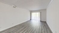 Located at 941 NE 169th St, Unit 218, in North Miami Beach, FL, this well-appointed 2-bedroom, 1-bathroom unit offers a thoughtfully designed layout across a single floor. The open kitchen and living area serve as the heart of the home, featuring sleek white cabinetry, a mosaic tile backsplash, quartz countertops, stainless steel appliances including a side-by-side refrigerator and dishwasher, and a peninsula that provides additional prep and dining space. Light gray luxury vinyl plank flooring runs throughout, lending a clean, contemporary aesthetic to every room. The spacious living room is bathed in natural light through a large sliding glass door fitted with vertical blinds, opening to a private balcony with lush tree canopy views. Both bedrooms are bright and well-proportioned, each featuring multiple windows with horizontal blinds that allow ample natural light and neighborhood views. Crown molding accents the ceilings, adding a refined touch. Built-in louvered closets offer generous storage in the bedrooms. The bathroom is finished with large-format stone-look tile on both the floors and shower surround, complemented by a full soaking tub and a window for natural ventilation. A dedicated hallway and closet complete this efficiently organized unit.