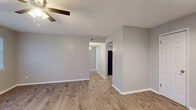 This single-story, 2-bedroom, 1-bathroom unit offers a thoughtfully arranged layout that maximizes its compact footprint. The living area features light wood-look laminate flooring, neutral gray walls, and a ceiling fan, creating a clean and functional space. A hallway connects the main living zone to the rest of the unit, with two interior doors visible from the entry area, which also benefits from recessed lighting and direct access to the front door.

The kitchen is equipped with gray shaker-style cabinetry, granite-look countertops, a double-basin stainless steel sink, and a black electric range, providing practical storage and workspace.

The spacious primary bedroom is the largest room in the unit, featuring two windows that allow ample natural light, wood-look flooring, and a ceiling fan with lighting. The second bedroom is finished with neutral carpet, a window, and a ceiling fan, offering a comfortable and private space.

The bathroom includes a tiled tub-shower combination with warm earth-tone tile surround, wood-look flooring, a vanity with granite-look countertop, and a large mirror. A dedicated closet completes the unit's storage offerings, contributing to the overall practicality of this efficiently designed home.