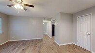 This single-story, 2-bedroom, 1-bathroom unit offers a thoughtfully arranged layout that maximizes its compact footprint. The living area features light wood-look laminate flooring, neutral gray walls, and a ceiling fan, creating a clean and functional space. A hallway connects the main living zone to the rest of the unit, with two interior doors visible from the entry area, which also benefits from recessed lighting and direct access to the front door.

The kitchen is equipped with gray shaker-style cabinetry, granite-look countertops, a double-basin stainless steel sink, and a black electric range, providing practical storage and workspace.

The spacious primary bedroom is the largest room in the unit, featuring two windows that allow ample natural light, wood-look flooring, and a ceiling fan with lighting. The second bedroom is finished with neutral carpet, a window, and a ceiling fan, offering a comfortable and private space.

The bathroom includes a tiled tub-shower combination with warm earth-tone tile surround, wood-look flooring, a vanity with granite-look countertop, and a large mirror. A dedicated closet completes the unit's storage offerings, contributing to the overall practicality of this efficiently designed home.