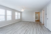 This single-floor residence offers a well-organized layout designed for comfortable everyday living. The spacious main living area is finished with light wood-look luxury vinyl flooring and features a ceiling fan, multiple windows with blinds that allow ample natural light, and a sliding glass door that opens to a private balcony with outdoor views. The open-concept design connects the living space directly to the kitchen, which is equipped with white cabinetry, a white subway tile backsplash, light stone countertops, a double-basin sink, a stainless steel dishwasher, and a black range. A breakfast bar with seating overhang provides a casual dining option.

A hallway with matching wood-look flooring connects the common areas to the private quarters. The bedrooms feature soft wall-to-wall carpet, ceiling fans, and windows that bring in natural light. The bathrooms are finished with wood-look flooring, white vanity cabinetry, light stone countertops, and a tub-shower combination. One bathroom includes an adjoining walk-in closet with built-in shelving. Neutral warm-toned walls and clean white trim throughout the space create a cohesive, move-in-ready aesthetic.