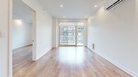Located at 2855 Ch Bates in Montréal, this well-appointed one-bedroom, one-bathroom unit offers a thoughtfully designed layout with modern finishes throughout. Light oak hardwood flooring runs continuously across the living areas and bedroom, creating a warm and cohesive aesthetic.

The open-concept kitchen is a standout feature, combining white lower cabinetry with rich wood-toned upper cabinets and a clean white countertop. Stainless steel appliances, including a range and French door refrigerator, complement the contemporary design. A central kitchen island provides additional workspace and serves as a natural divider between the kitchen and the bright, spacious living area.

The living area benefits from large floor-to-ceiling sliding glass doors that open to a balcony, flooding the space with natural light and offering views of the surrounding neighbourhood. Recessed lighting and a wall-mounted climate control unit add to the room's functionality.

The bedroom is a comfortable and quiet retreat, featuring a double-door closet and the same warm hardwood flooring found throughout the unit. The bathroom is finished with large-format light tile flooring, a floating wood-accented vanity with an undermount sink, a mirrored medicine cabinet, and clean white walls that create a bright, spa-like atmosphere.