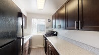 Unit 409 is a thoughtfully designed single-floor residence that combines modern finishes with a clean, functional layout. The kitchen serves as a standout feature, boasting rich dark cabinetry with sleek hardware, speckled stone countertops, a gas range, and a built-in skylight that floods the galley-style space with natural light. A window with horizontal blinds further brightens the kitchen and offers views of the surrounding exterior. Light wood-style flooring runs throughout the living and bedroom areas, creating a cohesive and contemporary aesthetic against the crisp white walls. The living area is generously proportioned and open, offering ample room for a variety of furniture arrangements. The bedrooms are well-sized, each featuring windows with natural light, and at least one includes a dedicated closet with a hanging rod for organized storage. The bathroom is finished in clean white with a full soaking tub and shower combination, complemented by a frosted window and built-in corner shelving for added practicality. Throughout the unit, consistent finishes, neutral tones, and wood-look flooring contribute to a bright, airy, and move-in-ready atmosphere.