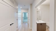 This thoughtfully designed 2-bedroom, 2-bathroom residence at 22 Jerome Ave in Bloomfield, CT offers a clean, contemporary aesthetic across a single floor. The open-concept kitchen and living area serves as the heart of the home, anchored by a sleek, oversized white quartz island with an integrated sink. Dark wood cabinetry contrasts beautifully with the bright white surfaces, while stainless steel appliances and a modern linear pendant light add refined touches. Light-toned hardwood flooring flows throughout the main living areas, enhancing the sense of openness and allowing natural light — drawn in through multiple large windows — to reflect warmly across the space. The living area benefits from abundant sunlight and views of the surrounding neighborhood. Both bedrooms are generously proportioned, with the primary bedroom offering ample space and plush carpet flooring for added comfort. Each room features large windows with shade treatments. The two bathrooms are finished with modern floating vanities featuring wood-toned cabinetry, white quartz countertops, and large mirrors. A well-lit hallway connects the bedrooms and bathrooms, maintaining a clean, functional flow. Throughout, crisp white walls, black hardware accents, and consistent high-quality finishes create a cohesive, move-in-ready modern living environment.
