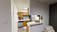 Located at 5101 Sanger Ave in Waco, Texas, this single-floor residence offers a well-organized layout designed for comfortable everyday living. The kitchen is efficiently arranged with warm wood cabinetry, a mosaic tile backsplash, light-toned countertops, and stainless steel appliances including a dishwasher, refrigerator, and electric range with overhead ventilation. A peninsula counter with a breakfast bar connects the kitchen to the adjacent dining area, which features rich, dark wood-look flooring that extends throughout the main living spaces. The dining area comfortably accommodates a round glass-top table and provides a welcoming space for meals. The living room is bright and inviting, with a large sliding glass door dressed with vertical blinds and sheer curtains that allow natural light to filter in. A ceiling fan fixture adds to the room's comfort. The bedroom is a spacious retreat with plush carpeting, a ceiling fan, a textured ceiling, and a window with curtains. A bold accent wall adds a distinctive design touch. The bathroom is clean and functional, featuring a wood-vanity with a light countertop, a large mirror, wall-mounted lighting, and wood-look flooring. Throughout the residence, textured ceilings and neutral wall tones create a cohesive and practical living environment.